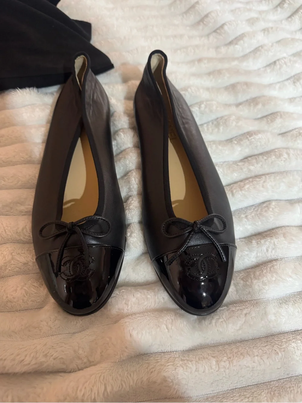 CHANEL Black Leather Ballet Flats with Patent Cap Toe and Bow Accent
